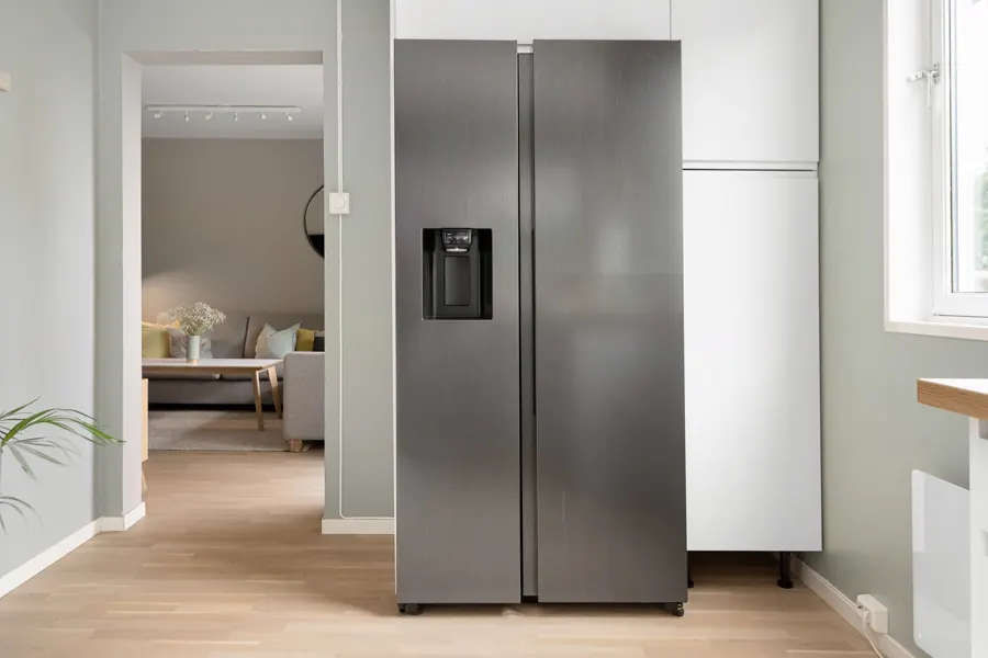 Geladeira de inox em uma cozinha ao lado da janela