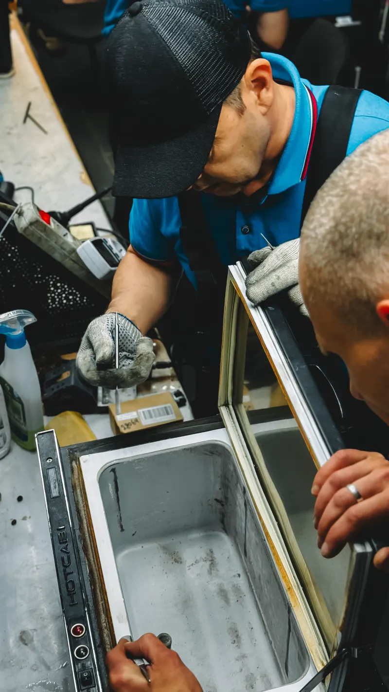 Dois técnicos trabalhando no reparo de um freezer